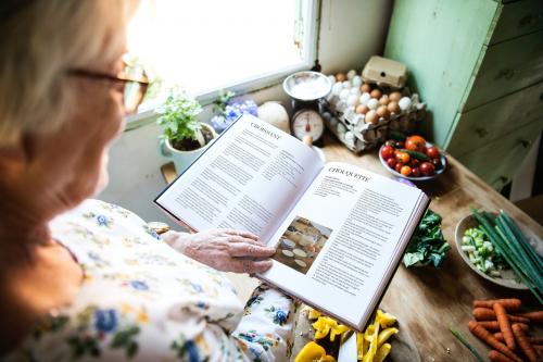 Happy elderly woman reading a cookbook - 484463