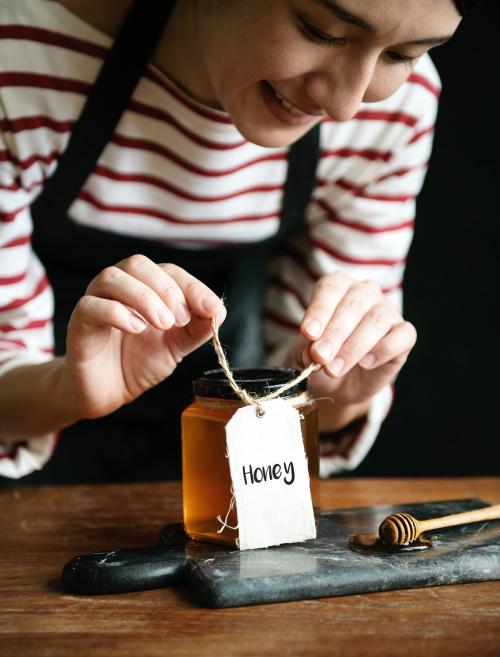 Woman packing organic honey into a jar - 484852