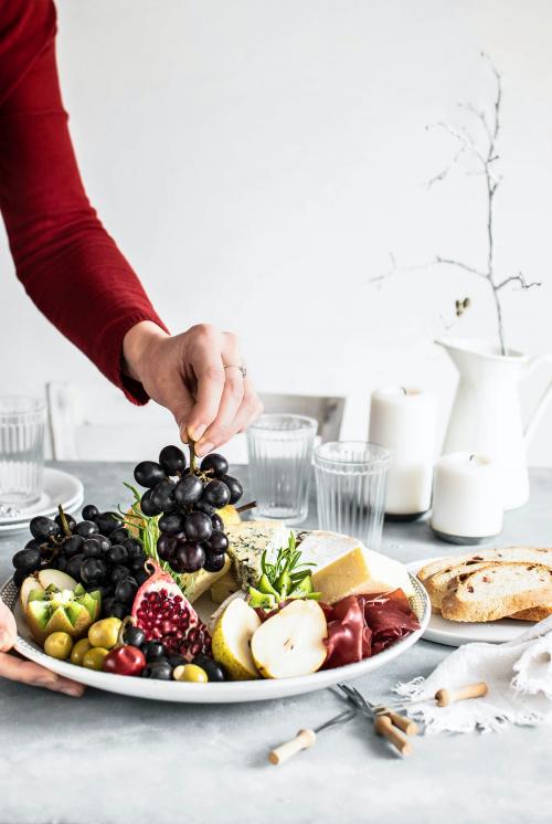 Woman preparing a cheese platter and bread - 2103301