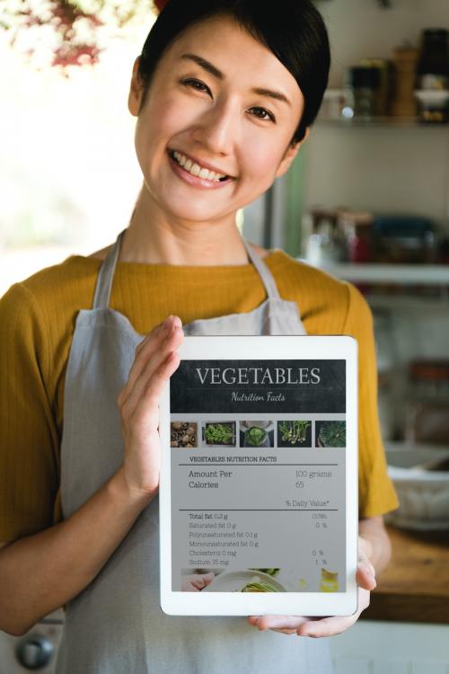 Happy woman holding a tablet with vegetable nutritional facts - 485573