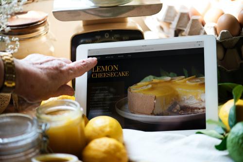 Woman reading lemon cheesecake recipe from a tablet - 485669