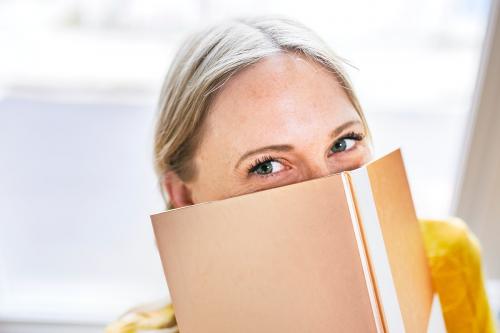 Woman hiding behind a shiny gold notebook - 2204578