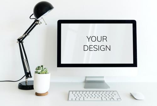 Computer on white table in workspace with black lamp and small plant - 2778