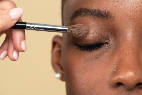 Makeup artist applying eye shadow on a black woman - 2254253