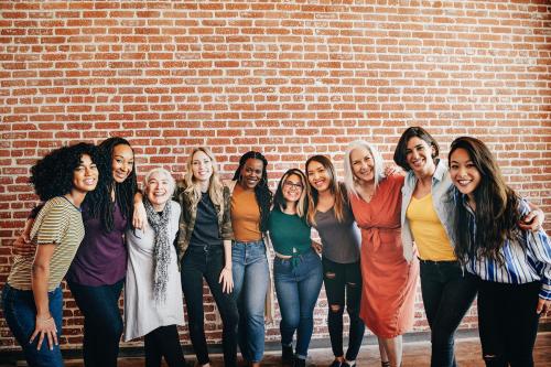 Cheerful diverse women standing in front of a red brick wall - 1223886