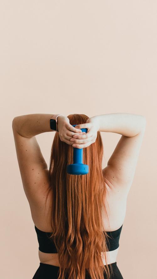 Rear view of woman lifting dumbbells to tone her arms mobile phone wallpaper - 1225103