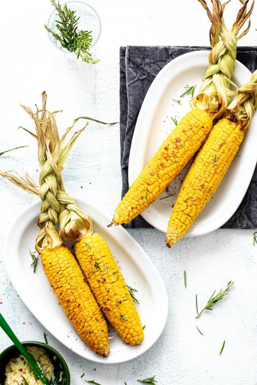 Fresh corn on the cob with organic rosemary leaves - 1225257