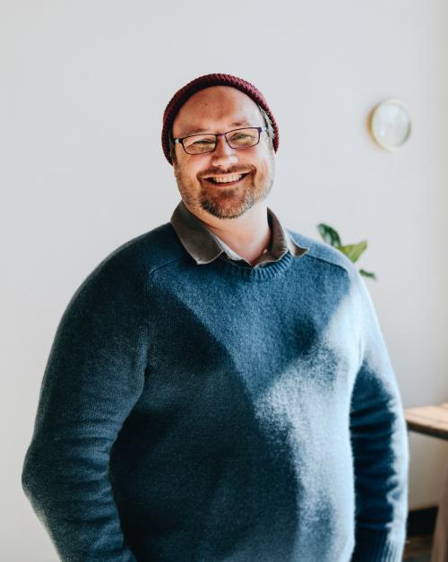 Cheerful man in a blue sweater and a red knitted hat - 1226761