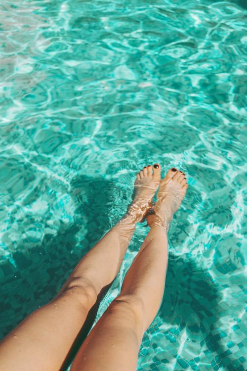 Woman putting her legs in the pool - 1228364