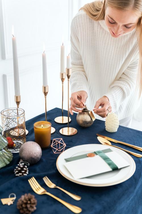 Blond woman setting up a Christmas dining table - 1231735