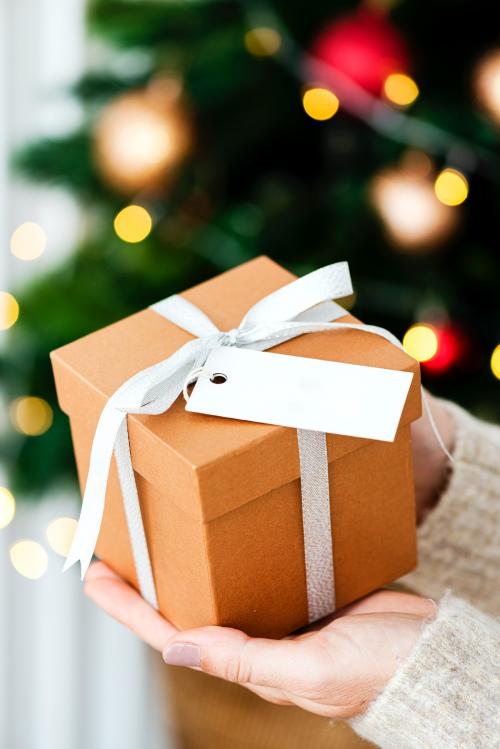 Woman holding a brown present with a white card - 1231765