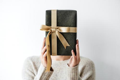 Woman covering her face with a gray present - 1231837