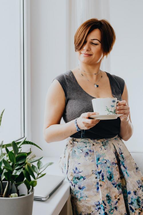 Woman holding a cup of tea by the window - 937367