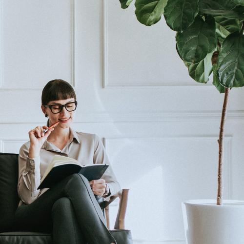 Casual young woman sitting on a couch with her planner - 1216807