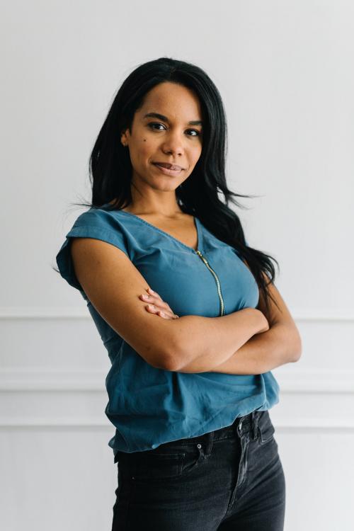 Happy empowering black woman standing by a white wall - 1220763