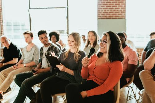 Cheerful woman speaking on a microphone in a workshop - 1223889