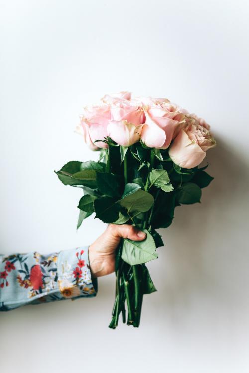 Woman holding a bouquet of flowers by the wall - 1226531