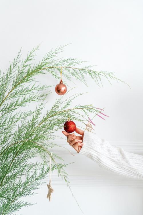 Woman hanging a red bauble on a Christmas tree - 1231733