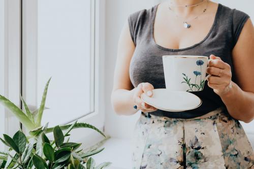 Woman holding a cup of tea by the window - 937442