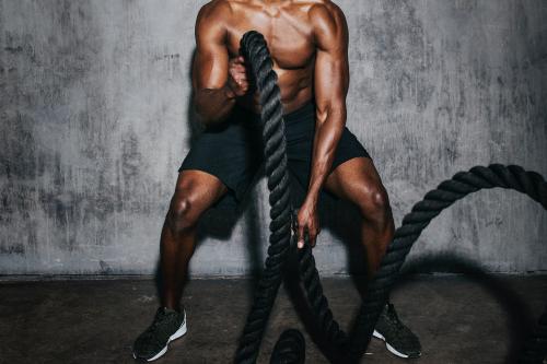 Muscular man doing a battle rope in a gym - 1222520