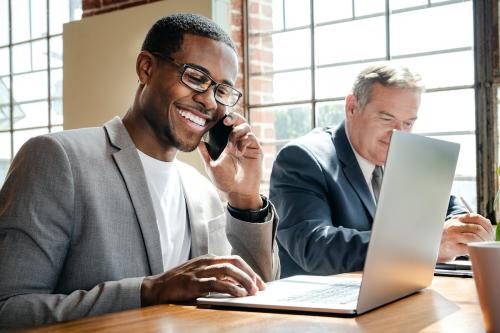 Businessman talking on a phone while using a laptop - 1226713