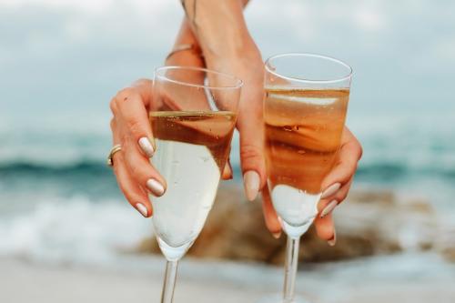 Women with glasses of champagne at the beach - 1228365