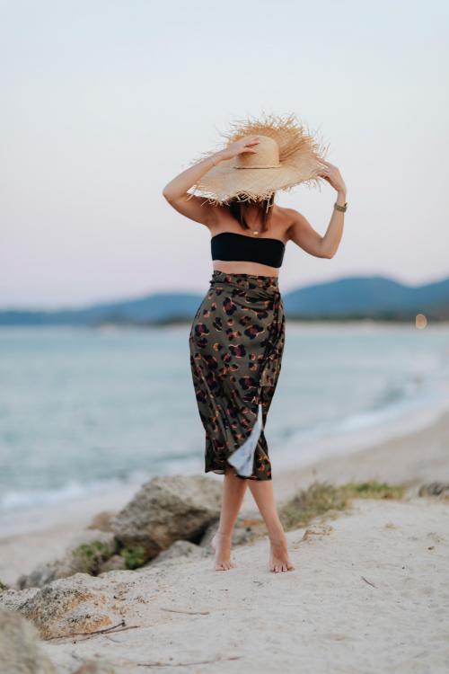 Woman wearing a straw hat walking alone the beach - 1228386