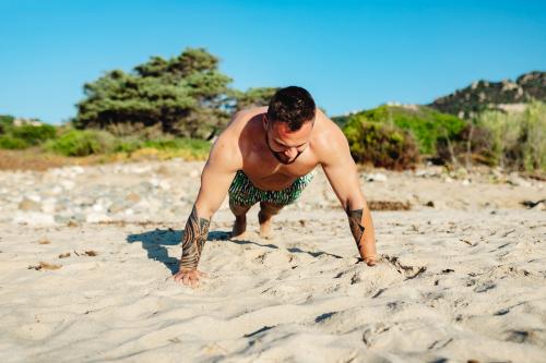 Tattoo man doing a push up at the beach - 1228409