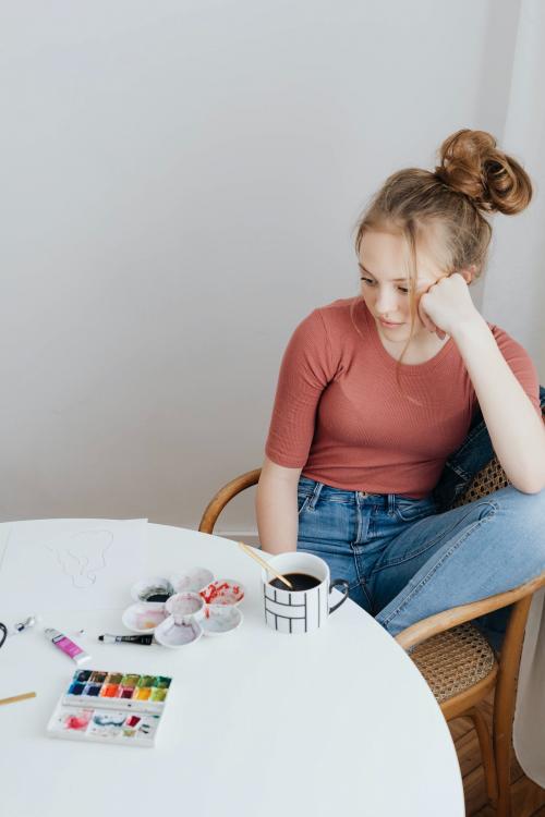 Female artist sitting thoughtfully while looking at her artwork - 592724