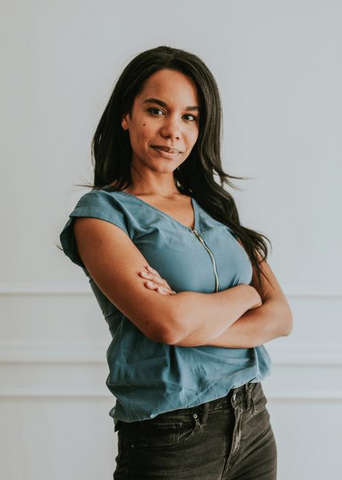 Happy empowering black woman standing by a white wall - 1220841