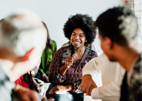 Cheerful woman speaking on a microphone in a workshop - 1223841