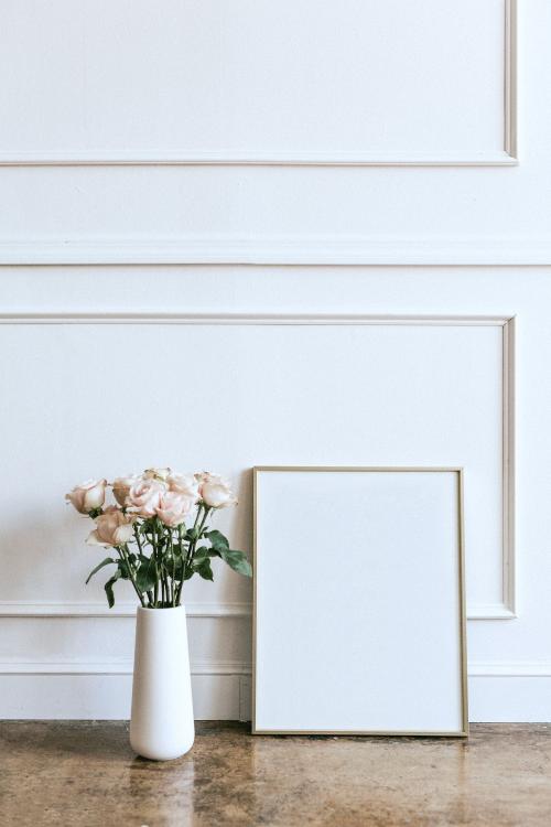 Frame against a white wall by a vase of flowers - 1224418