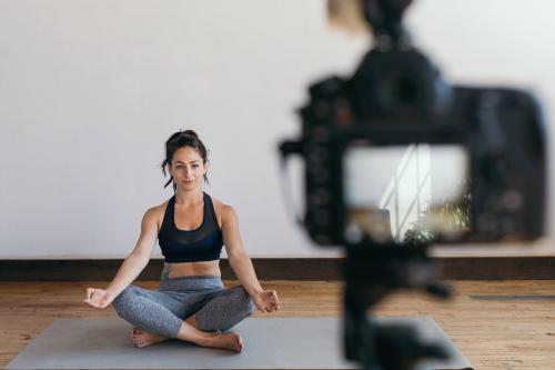 Yoga blogger recording a video while in a padmasana pose - 1225409