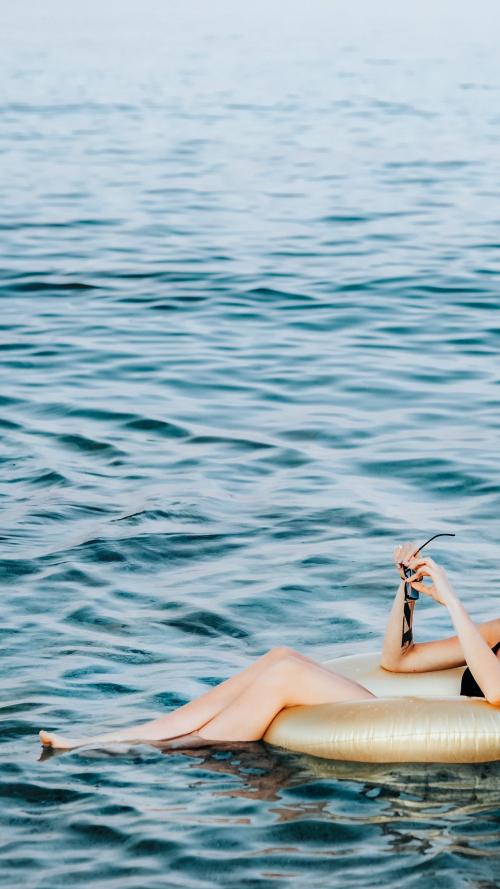 Girl sitting on a gold swim tube in the ocean mobile phone wallpaper - 1228370