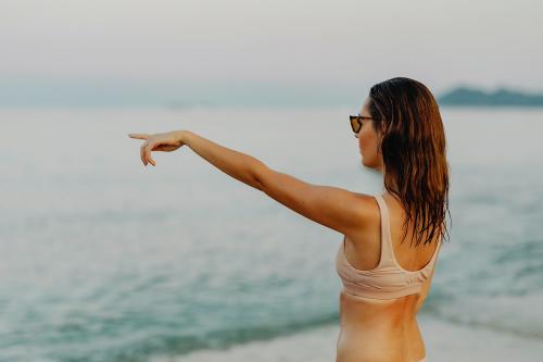 Girl in a beige bikini pointing out to the sea - 1228402