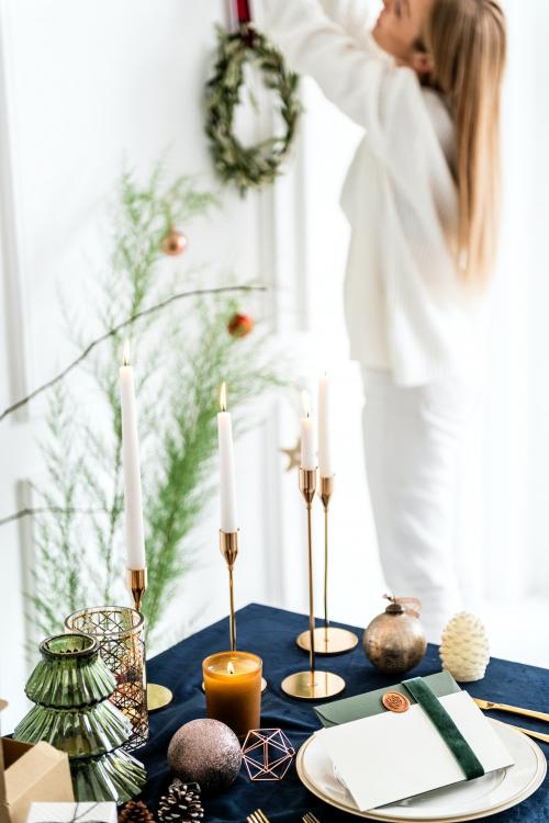 Woman hanging a Christmas wreath next to a dining table - 1231797