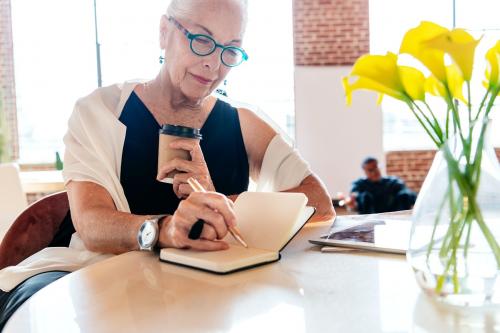 Mature woman writing a journal in her office - 2019890