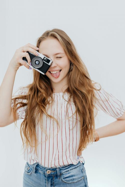 Playful woman taking a picture with a film camera - 592708