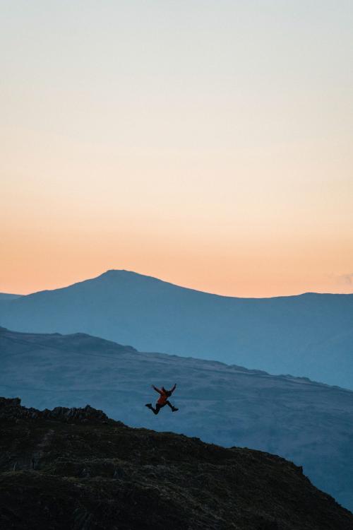 Woman jumping on a summit of Loughrigg Fell at Lake District in England - 935996