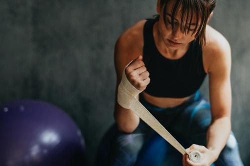 Female boxer putting a strap on her hand - 1222507