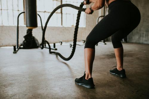 Sportive woman doing a battle rope in a gym - 1222509