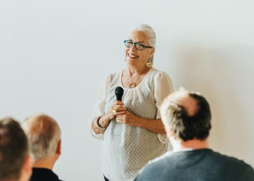 Cheerful elderly woman speaking on a microphone in a seminar - 1223784