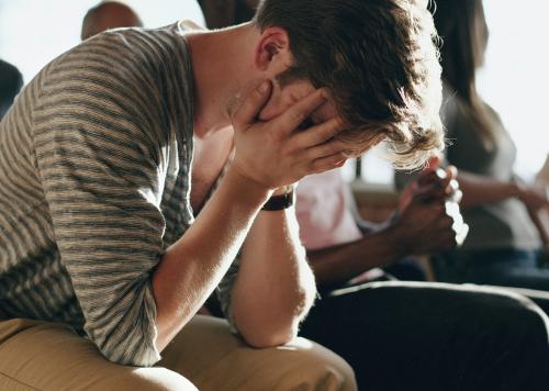 Depressed man sitting in a rehab session - 1223802