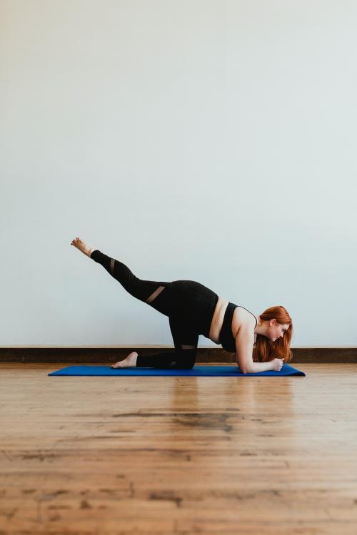 Sporty woman stretching her legs on a yoga mat - 1225117