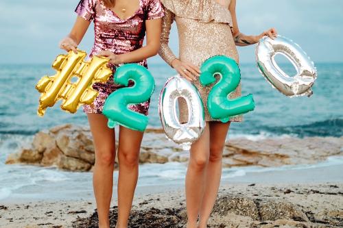 Girls carrying a 2020 foil balloon at the beach party - 1228403