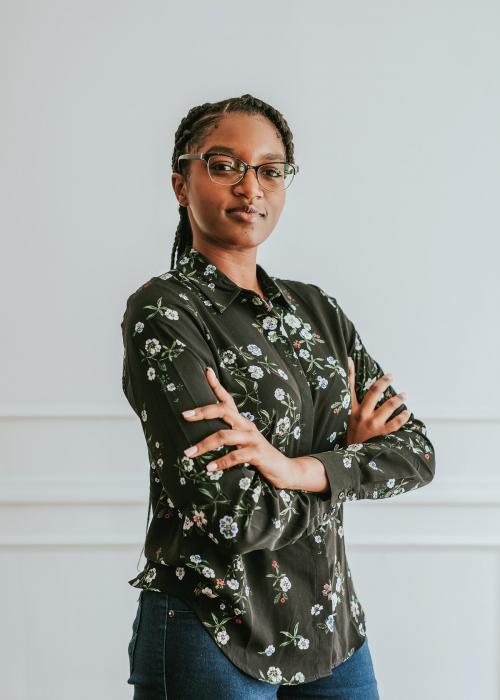 Happy empowering black woman standing by a white wall - 1220842