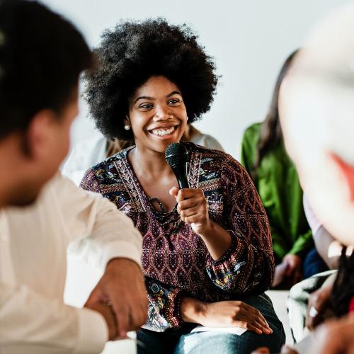 Cheerful woman speaking on a microphone in a workshop - 1223884