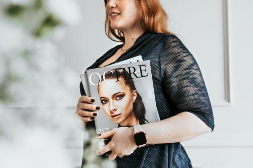 Woman wearing a smartwatch and holding a magazine - 1224376