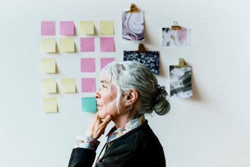 Senior businesswoman brainstorming ideas on a wall - 1226459