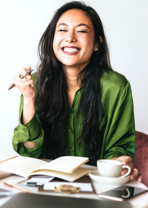 Happy woman writing a journal in her office - 1226524